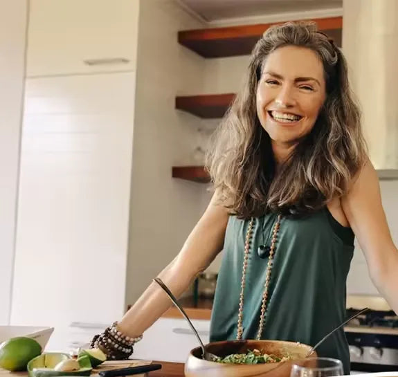 Smiling woman preparing a fresh salad in a bright home kitchen